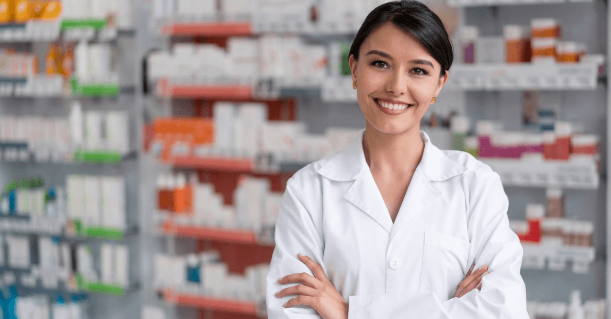 Pharmacist in a white coat in front of dispensing shelves